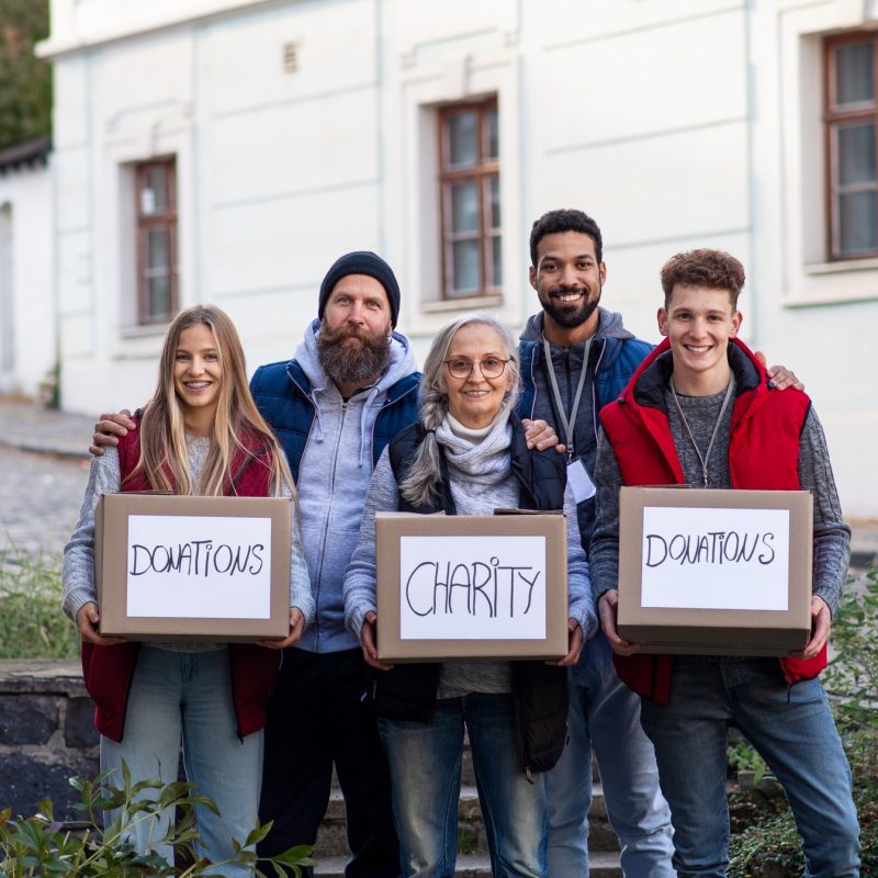 Diverse group of volunteers with donation boxes standing outdoors, social care and charity concept Diverse group of volunteers with donation boxes standing outdoors, social care and charity concept