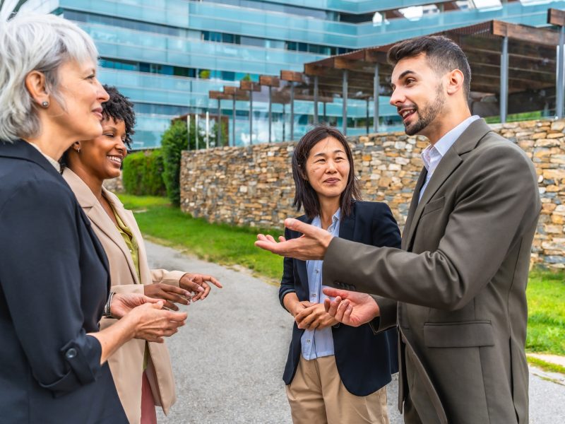 Multi-ethnic relaxed business colleagues talking outside in the city Multi-ethnic relaxed business colleagues talking outside in the city